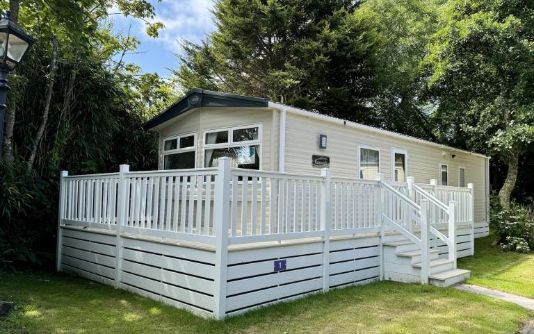 Outside View of a Caravan Holiday Home with a Decking area surrounded by Trees