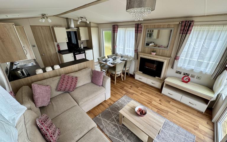 Interior view of the living room, with L shaped sofa, fireplace, TV and TV stand.